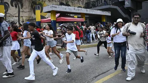 Getty Images People run into a street away from buildings following an earthquake in Caracas, Venezuela on 24 June.