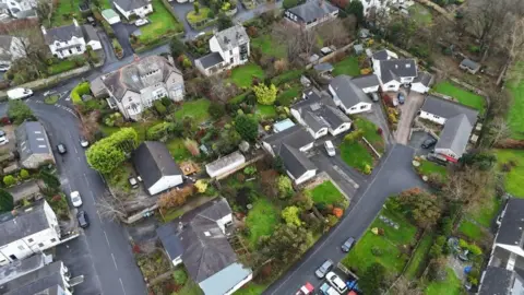 An aerial view of a residential area full of large houses surrounded by trees and greenery