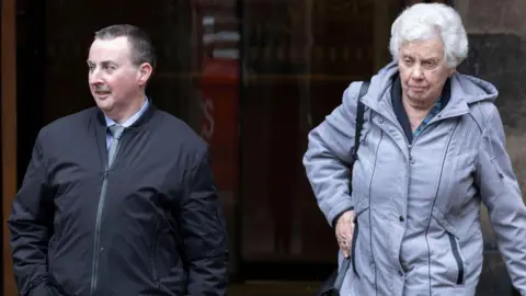 Steven and Jennifer Robertson outside the High Court in Edinburgh. He is wearing a blue jacket, light blue shirt and light blue patterned tie 