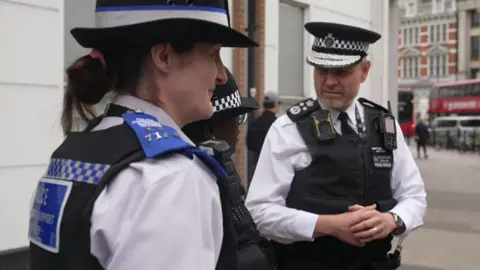 Matt Jukes stands on a high street talking to two other uniformed police officers 
