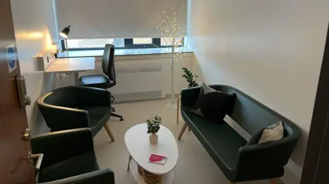 The newly opened bereavement suite, a small room with a sofa, coffee table and two chairs, a desk and illuminated ornamental tree