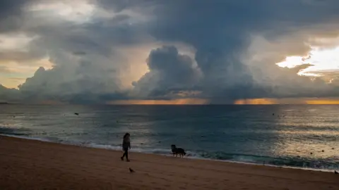 PA Media Woman walking on beach