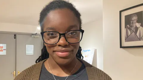 BBC News Nyarai smiling at the camera. She is wearing glasses and has her hair pulled back.