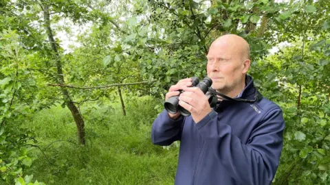 Dr Rob Lambert holding binoculars