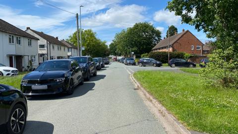 Cars parked along a residential street and on a junction