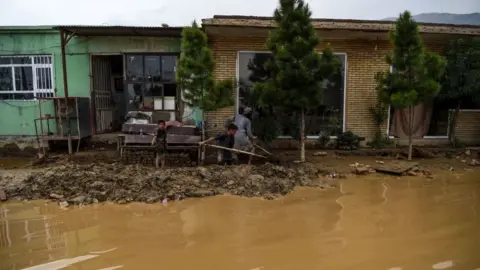 AFP Villagers use shovels to clear the mud on the roadside after flash floods killed at least 162 people in Afghanistan in August 2020 (file picture).