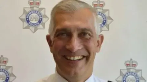 Humberside Police Paul Anderson smiling to the camera with logos of Humberside Police in the background on a board