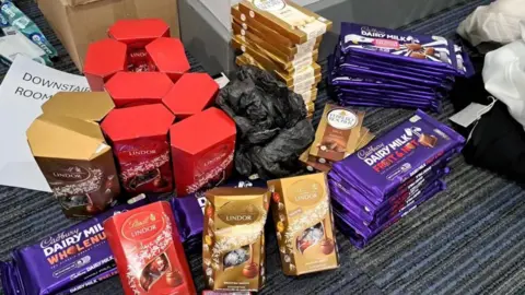 Boxes and bars of chocolate are lined up on a carpet.