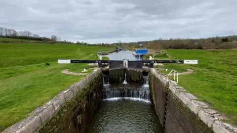 Ken Rayner Looking along a lock as the water pours in. Fields are on either side.