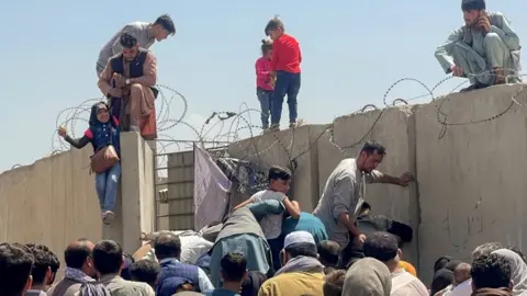 Reuters A man pulls a girl to get inside Hamid Karzai International Airport in Kabul, Afghanistan August 16, 2021