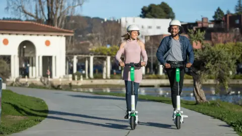 Lime Two people riding Lime Scooters