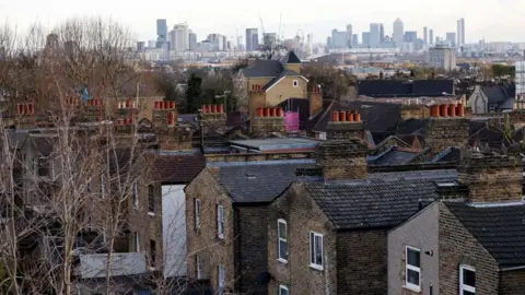 AFP/Getty Images File image showing an aerial view of streets and houses in London, with the city skyline behind.