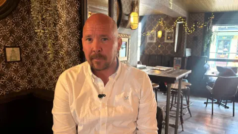 Aidan Lavin sitting on a bar stool in his pub, the Raven and Bine in Southampton