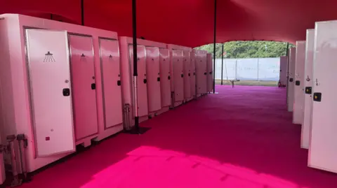 George King/BBC Rows of pink shower cubicles.