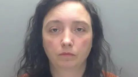 Durham Police Mugshot of Paula Roberts. She has long black curly hair and her face is showing no emotion 