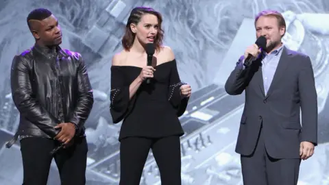 Getty Images Rian Johnson (right) with John Boyega and Daisy Ridley