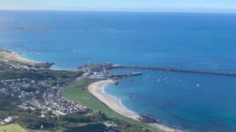 A drone shot of Alderney with part of the island's harbour as well as expansive sea