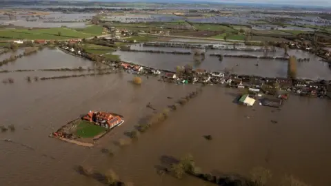 PA Media Moorland, Somerset in 2014, with houses and fields under floodwater