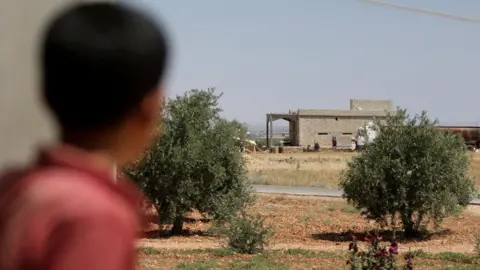 AFP A boy looks at a house in the village of al-Hamira, northern Syria, that was reportedly targeted in a raid by US-led coalition forces that led to the capture of a senior IS leader (16 June 2022)