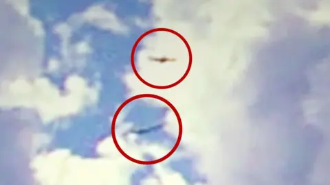 Two planes point in the same direction midair with a red circle around each