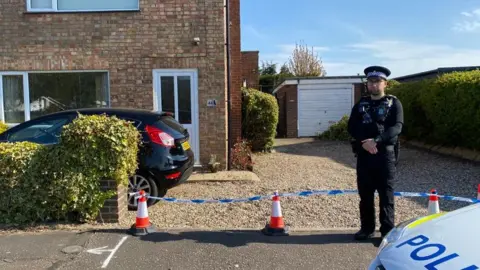 BBC Police officer outside a house on Yarmouth Road, Kirby Cane