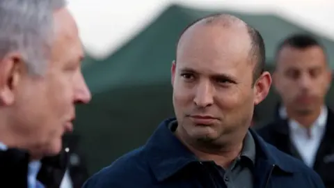 Reuters Benjamin Netanyahu (L) speaks to Naftali Bennett (R) during a visit to an Israeli army base in the occupied Golan Heights (24 November 2019)