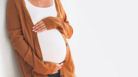 Getty Images Pregnant woman with her hands around her belly