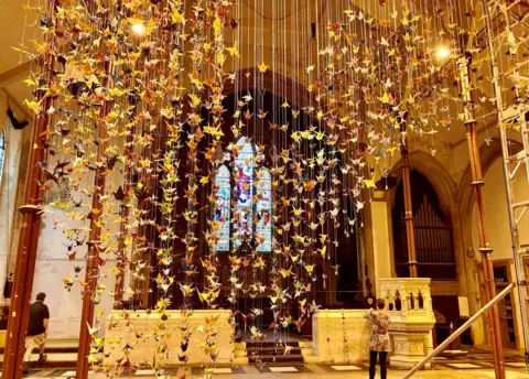 BBC Thousands of paper cranes had been hand-folded to represent those who have died