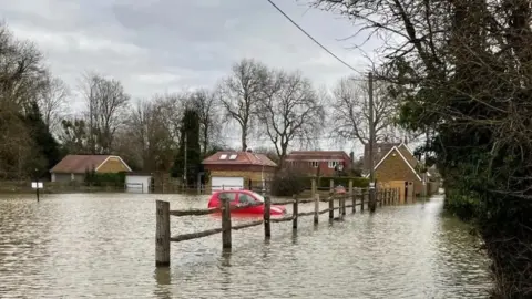 A car is underwater in front of houses