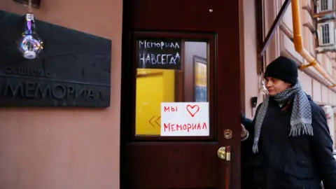 Reuters A man enters an office of the human rights group Memorial in Moscow, Russia. Placards read: "Memorial forever" (top) and "We love Memorial". Photo: December 2021