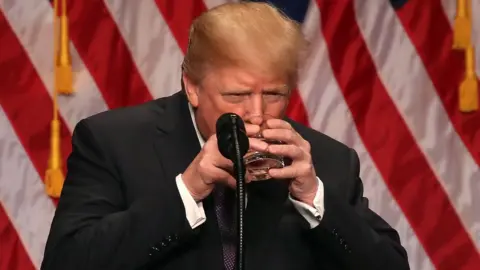 Getty Images U.S. President Donald Trump drinks from a water glass he holds with two hands during a speech at the Ronald Reagan Building on December 18, 2017 in Washington, DC.