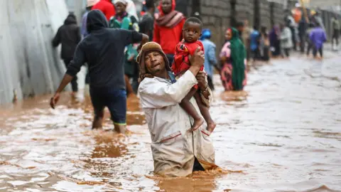 A man holding a child above flood waters in Kenya