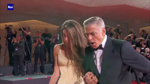 Amal and George Clooney look  shocked connected  seeing a lensman  falling