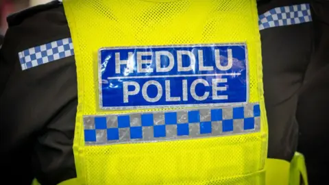 A police officer uniform with 'Heddlu Police' on the back 