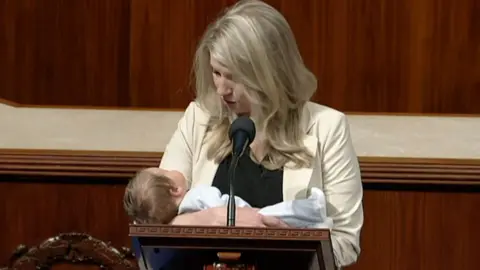 Congresswoman holds baby in front of podium