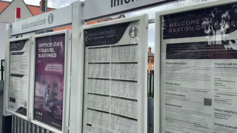 The photo shows four information boards at a railway station. They all have different writing on them. Above are signs which read 'information.' 