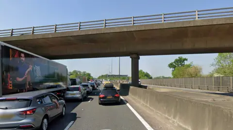 M25 in Surrey full of traffic with Cobham road bridge above