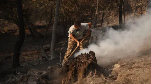 Europa Press via Getty Images A man attempts to extinguish the remaining flames from the wildfire on the outskirts of Casavieja, on 29 July, 2026 in Avila, Castile and Leon, Spain