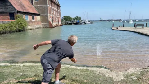 A man skims a stone across the water at Ashlett Creek public hard