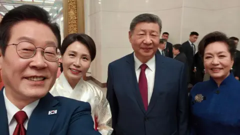 X / Lee Jae Myung Selfie taken by Lee Jae Myung shows him with Xi Jinping and their wives smiling for the camera