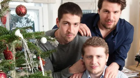 Family photo Jordan with his brothers next to a Christmas tree