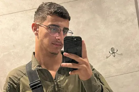 Selfie photograph  of IDF infantry worker  Shimon Malka. He has abbreviated  brownish  hair, is wearing glasses and has a tiny  beard connected  his chin. He is holding his mobile telephone  taking selfie successful  a mirror.