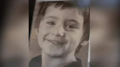 Family handout Daniel Klosi is seen smiling in a black-and-white portrait image. He is seen from the neck up.