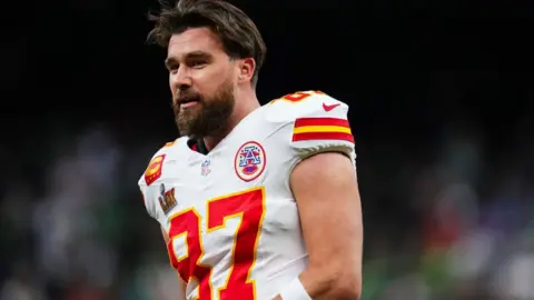 Getty Images Travis Kelce, dressed in American football gears, smiles