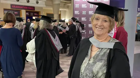 Tom MacDougall/BBC Janice Hopson stood in her own cap and gown.