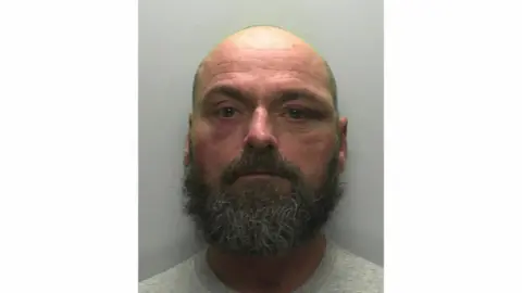 Devon and Cornwall Police Police mugshot of Shaun McCormick, a man with large dark and grey beard and bald head