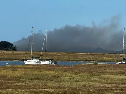 Garry Platten Smoke from the fire at East Hills and boats in an estuary