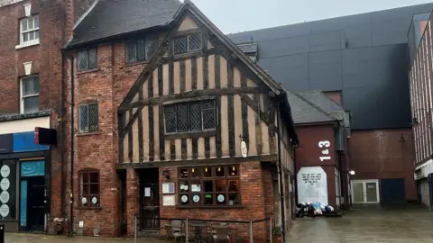 A 1600s style three story red brick building with timber panelling 