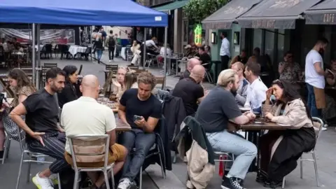 Getty People sat at dining tables outside restuarants