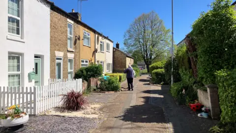 Shariqua Ahmed/BBC A long street with houses on either side.